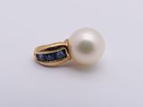 a close up of a pearl and sapphire ring on a white surface