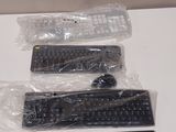 four keyboards and two remotes wrapped in plastic on a table