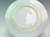 a white plate with a gold rim sitting on a stand