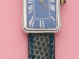 une montre posée sur un support rose, avec un bracelet bleu