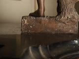 a statue of a child standing on a piece of wood