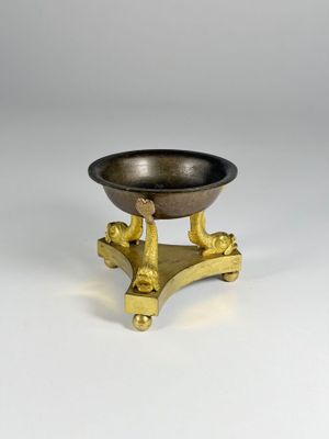 an image of a small brass bowl on a stand on a white surface