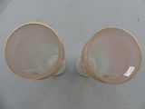 pair of pink glass vases with gold rims sitting on a table