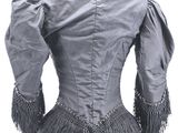 the back of a woman ' s jacket with fringes on it