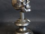 two silver candles that have a skull on top of them