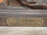 a bronze statue of a woman sitting on top of a table