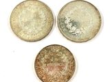 three different types of coins sitting on top of a white surface