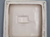 a small square white container with a handle on a table