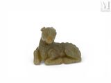 une petite statue représentant un mouton couché sur une surface blanche