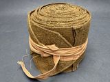 une corde enroulée autour d'un rouleau de papier kraft posé sur une surface grise