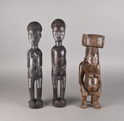 deux figurines en bois représentant un homme et une femme portant un panier sur la tête