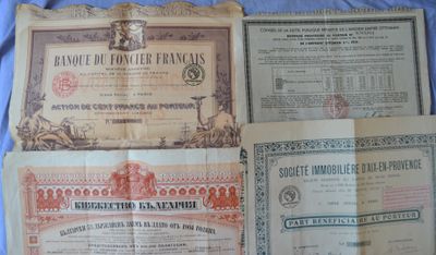 three old paper certificates sitting on top of a blue sheet