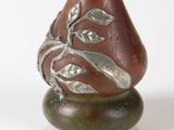 a brown vase with a leaf on it on a table
