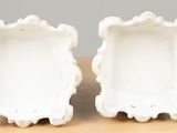 pair of white ceramic vases sitting on top of a wooden table