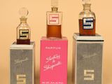 trois petits flacons de parfum posés sur des boîtes, sur une table