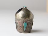 an old silver vase with a turquoise stone in it on a white surface