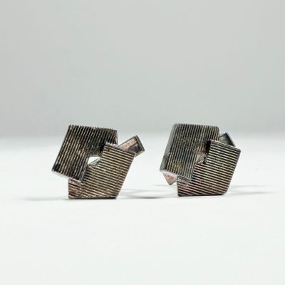 deux pièces métalliques argentées sont posées sur une surface blanche