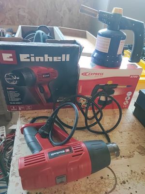 une perceuse rouge et noire et une boîte à outils posées sur une table