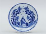 an image of a blue and white plate with a woman sitting on a bench