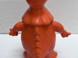 an orange plastic bear with a red hat on it ' s head