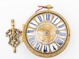 a gold clock with roman numerals and a key