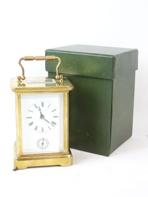 a small clock sitting next to a box on a white surface