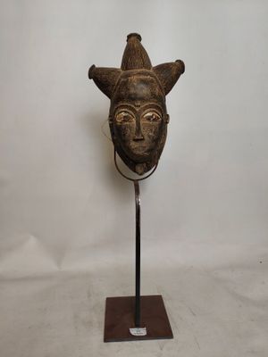 image d'un masque en bois sur un support sur fond blanc