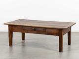 une vieille table basse en bois surmontée d'un tiroir