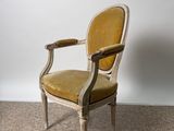 an old chair with a yellow upholstered seat on a carpeted floor