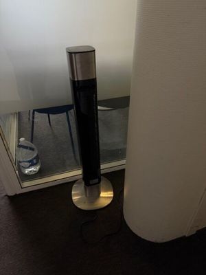 a black and silver speaker on a stand next to a window