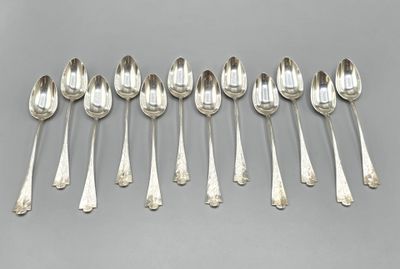 six cuillères en argent sont alignées sur une surface grise