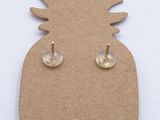 a close up of a pair of pineapple earrings on top of a piece of cardboard