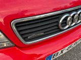 the front grille of a red car with a number plate on it