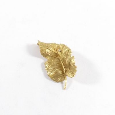 broche en feuille d'or sertie de diamants sur fond blanc