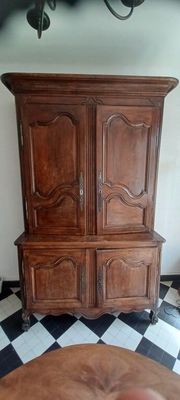 une armoire en bois dans un coin d'une pièce au sol carrelé en damier noir et blanc