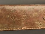 an old brown leather belt with a metal buckle on a gray background