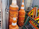 several orange traffic cones are stacked on top of each other in front of a fence