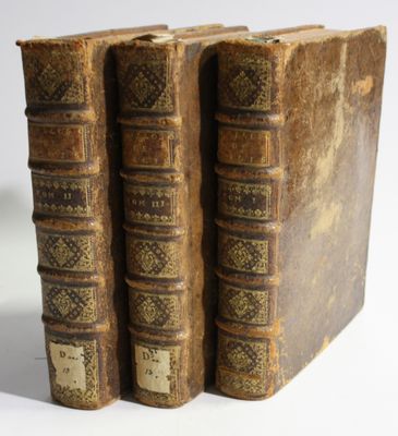 two old books sitting on top of each other on a white surface