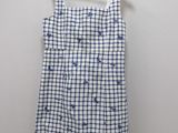 a white and blue checkered dress hanging on a hanger