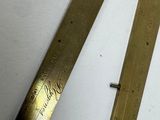 two brass rulers on a white surface next to each other