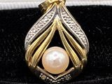 a close up of a gold and silver pendant with a pearl in it