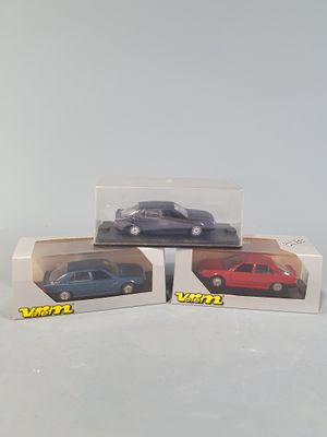 three toy cars are in a box on a white surface