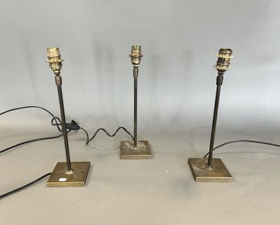 three brass table lamps with black cords and a white background