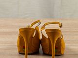 pair of yellow high heeled shoes sitting on top of a wooden table