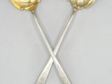 two silver spoons and a fork on a white surface