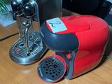 a red coffee maker sitting on a table next to a black chair