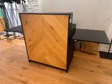 une armoire en bois avec un plateau noir, posée sur un parquet