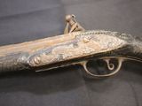 an old gun that is on display on a black surface