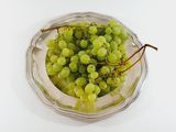 a bowl of green grapes sitting on a white table