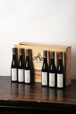 six bouteilles de vin sont posées dans une caisse en bois sur une table